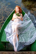 schöne junge verlassene Frau, Braut, Lady of Shalott, liegt sehnsüchtig verlassen mit Blumenstrauß in einem Boot und wartet voller Todessehnsucht auf den verflossenen Liebsten