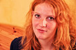 Schönes Portrait in Nahaufnahme einer offen lächelnden jungen rothaarigen lockigen Frau im Schlafzimmer mit Textfreiraum