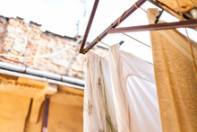 Closeup Of Yellow Hanging Clothes In Summer With Bedding Linen And Towels Drying On Rack Clothesline Line In Ukraine By Old Vintage Lviv Ukrainian Apartment Buildings