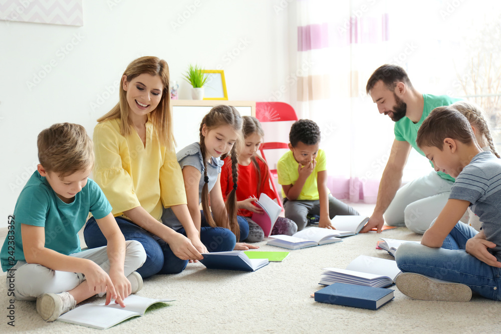 Teachers helping children with homework in classroom at school