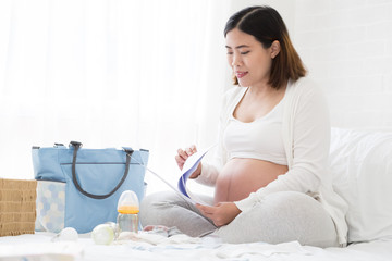 Pregnant woman preparing hospital bag checklist and making a birth plan from a hospital that has antenatal care for safety of the baby, Planning prenatal concept