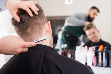 fashionable guy stylist creating haircut for man client at hairdressing salon