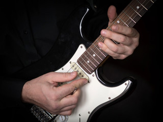 Male hands playing on electric guitar, close up, selected focus