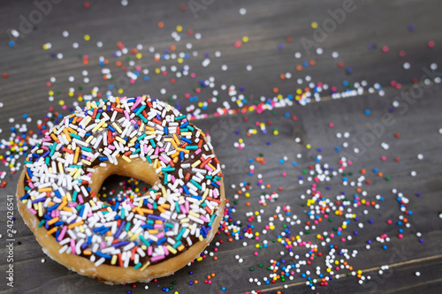 Fotografía donuts with chocolate frosting, topping sprinkles donut Colorful variety and Variety of flavors mix of multi colored sweet donuts with frosted sprinkled on a wooden background