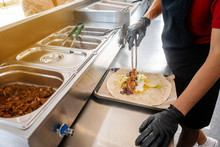 Woman Preparing Burrito In A Food Truck Putting The Ingredients In Tortilla Bread