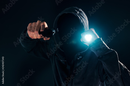 Fotografía Armed robbery, criminal with gun and torchlight attacking in dark