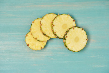 top view of sliced pineapple circles on turquoise wooden table