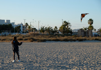 girl playing with kite n the beach during winter season at sunset - free time concept.