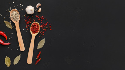 Pink and white peppercorns in spoons on dark background