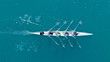 Aerial drone bird's eye top view of sport canoe operated by team of young men in open sea