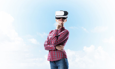 Girl in checked shirt wearing VR glasses experiencing another re