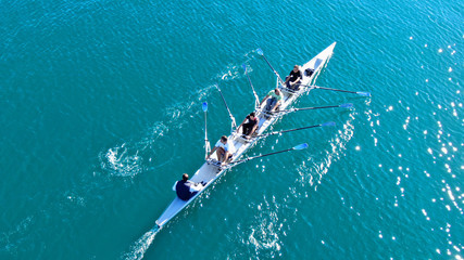 Wall Mural - Aerial drone bird's eye view of sport canoe operated by team of young women in emerald clear sea
