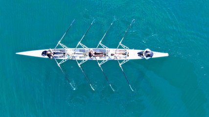 aerial drone top down view of sport canoe operated by team of young women in emerald clear sea