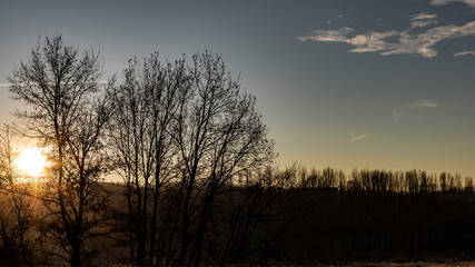 Sun flare shining over a blue dusk sky and foggy landscape