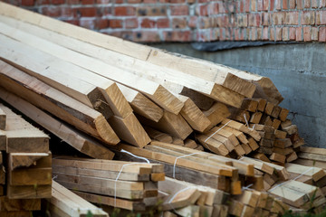 Poster - Close-up of piled stack of natural brown uneven rough wooden boards lit by bright sun. Industrial timber for carpentry, building, repairing and furniture, lumber material for construction.