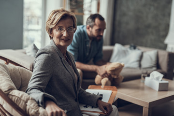 Wall Mural - Friendly psychotherapist turning in armchair and smiling