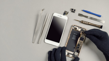 technician or engineer disassembling components broken smartphone and take off logic board for repai