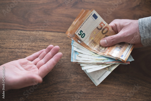 Fotografía hand of one person handing over cash to another