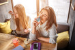 © estradaanton - Young women sit at table and smell parfume. Brunette hold blue bottle. They have rest and relax.