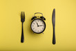 © Pixel-Shot - Alarm clock and cutlery on color background. Diet concept
