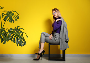 Wall Mural - Fashionable young woman sitting near color wall