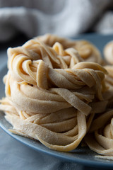 Homemade uncooked pasta noodle with flour over grey background. Food background. Copy space for text.