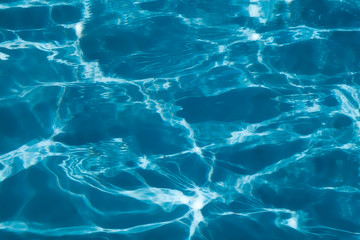 Wall Mural - Blue and bright ripple water surface in swimming pool with sun reflection.