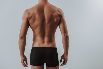 Back of muscular man in black underwear standing alone