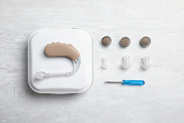 Flat lay composition with hearing aid and accessories on table