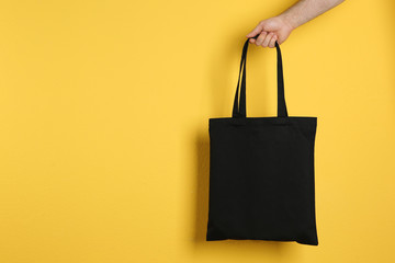 Wall Mural - man holding cotton shopping eco bag on color background. mockup for design
