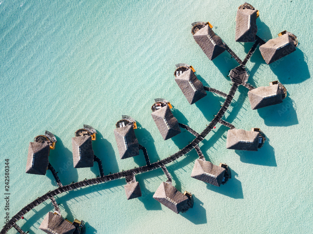 Luxury overwater villas with coconut palm trees, blue lagoon, white sandy beach at Bora Bora island, Tahiti, French Polynesia - obrazy, fototapety, plakaty 