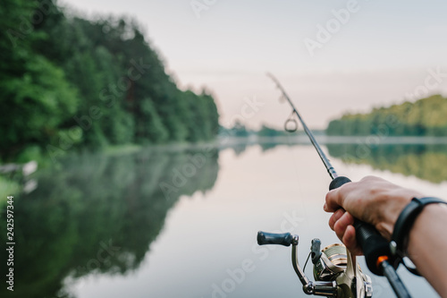 Cuadros en Lienzo Fisherman with rod, spinning reel on the river bank