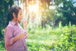 © brain2hands - Asian girl wearing a pink shirt, being within the Park. She is currently blowing soap bubbles with fun. In the midst of the evening sun, concept of fun and freedom with copy space.