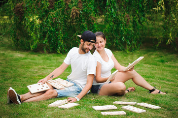 Wall Mural - Young man and woman playing giant dominoes in the Park on the grass.