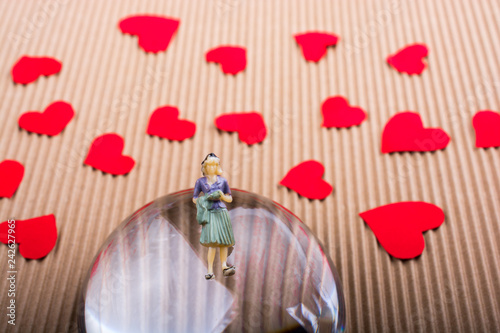 Fotografie, Obraz Woman figurine on half a globe with paper hearts