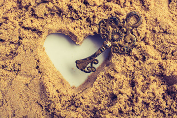 Wall Mural - Retro style key and a heart shape on brown sand