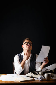 Book writer wearing white shirt sitting at the table with typewriter and imagine new characters of his new book