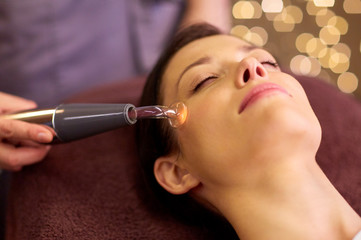 people, beauty, cosmetology and technology concept - beautiful young woman having needle free mesotherapy or hydradermie facial treatment by microcurrent firming device in spa