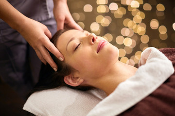 people, beauty, lifestyle and relaxation concept - beautiful young woman lying with closed eyes and having head massage at spa