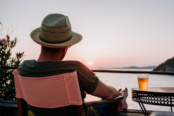 Sticker - Young man enjoying beer and sunset in a beach bar