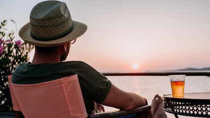 Sticker - Young man enjoying beer and sunset in a beach bar