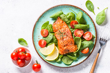 Baked salmon fish fillet with fresh salad top view on white.