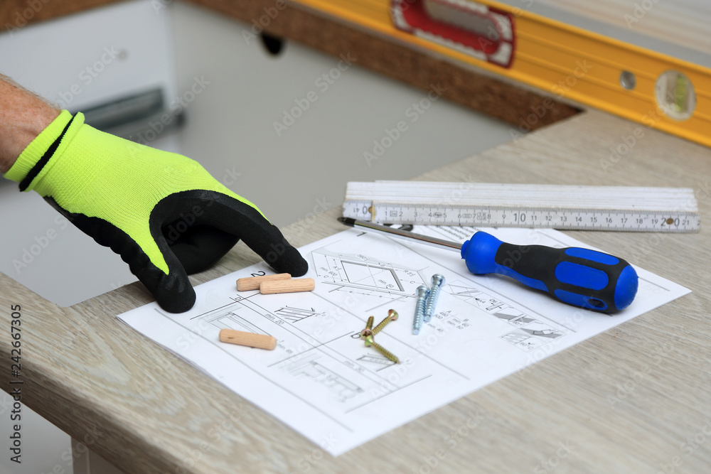 Pracownik pokazuje palcem na rysunku technicznym do montarzu mebli. - obrazy, fototapety, plakaty 
