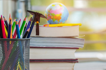 Education Graduate study concept: Black Graduation hat on pencils, blur of europe earth world globe on stack textbook at university classroom. Ideas knowledge learning success, Back to School