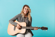 Smiling Young Girl Playing A Guitar While Sitting Isolated