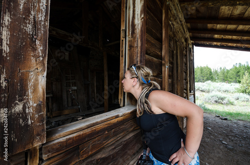 Woman Urban Explorer Looks Through A Broken Window In An Old Log