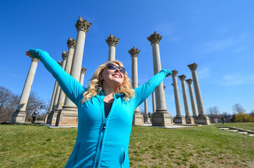 A female raises her arms next to the Capital Columns at the Washington DC National Arboretum. Concept for freedom