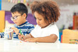 © rachaphak - Little toddler girl and boy concentrate  drawing together.  Asian boy and Mix African girl learn and play together in the pre-school class. Children enjoy hand writing. Friendship in class.