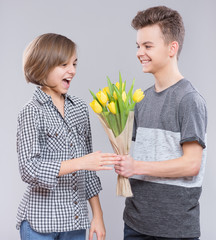 Wall Mural - Boy Giving Tulips for Girl. Holidays, Love, Happiness and People concept - Happy Child celebrating Valentines Day. Teen Boy and Girl with Flowers. 