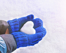 Female Hands In Knitted Mittens With Heart Of Snow In Winter Day. Love Concept. Valentine Day Background.